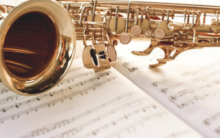 Closeup of a beautiful and shiny golden saxophone lying on music notes.