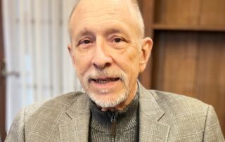 Photo of Interim Executive Director Freeman Burr sitting in office chair