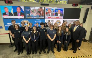 Criminal Justice and Protective Services students stand in front of a new Emergency Operations Center TV screen with CTECS and State of CT leadership;